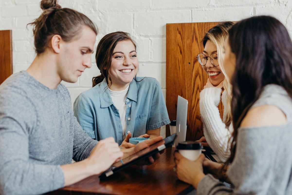 Four friends laughing together around a table